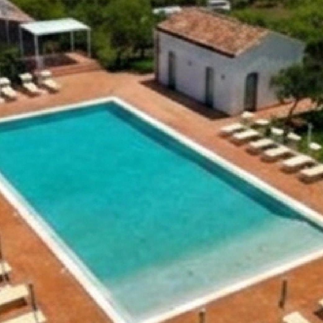 The pool of a restored masseria, ringed by sun loungers